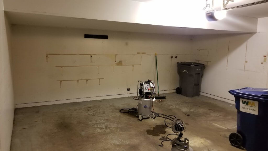 A bare, dimly lit garage after all the clutter has been cleared away but prior to the start of the remodel work.