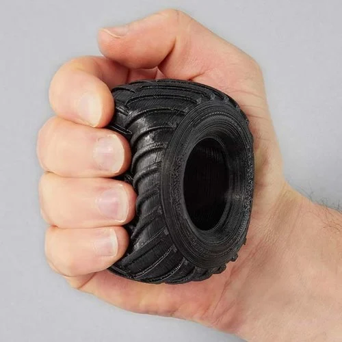 A Tire, 3D printed out of TPU material, is shown being squeezed in the palm of someone's hand.